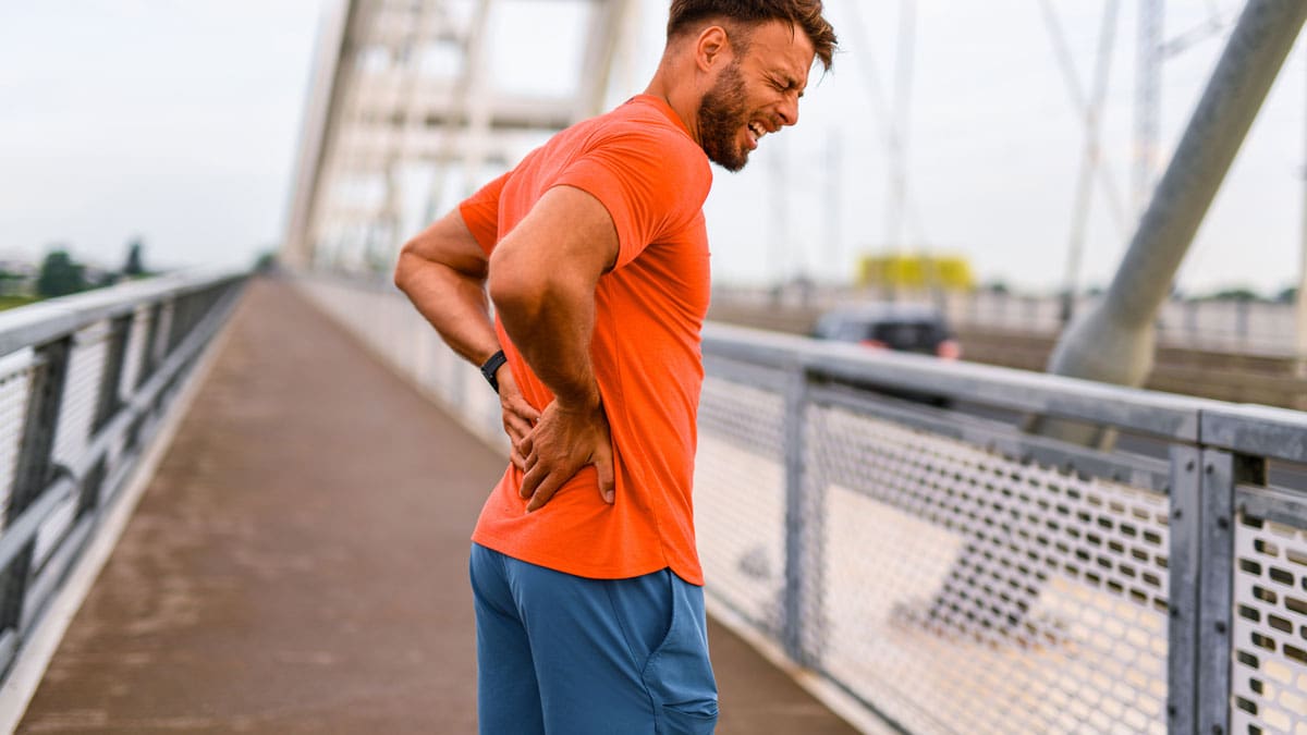 man-outdoors-holding-his-lower-back-during-a-walk