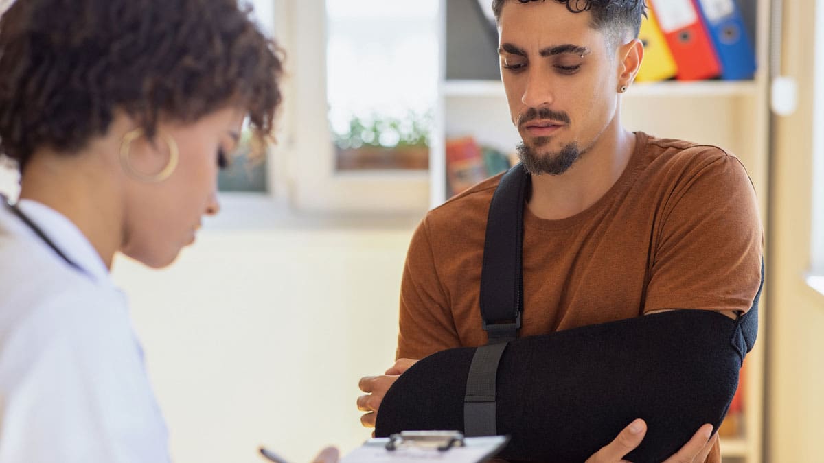 nurse-assisting-patient-with-arm-in-sling