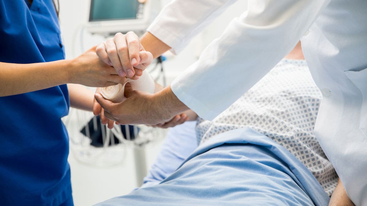 nurses-assisting-a-patient-lying-in-a-hospital-bed
