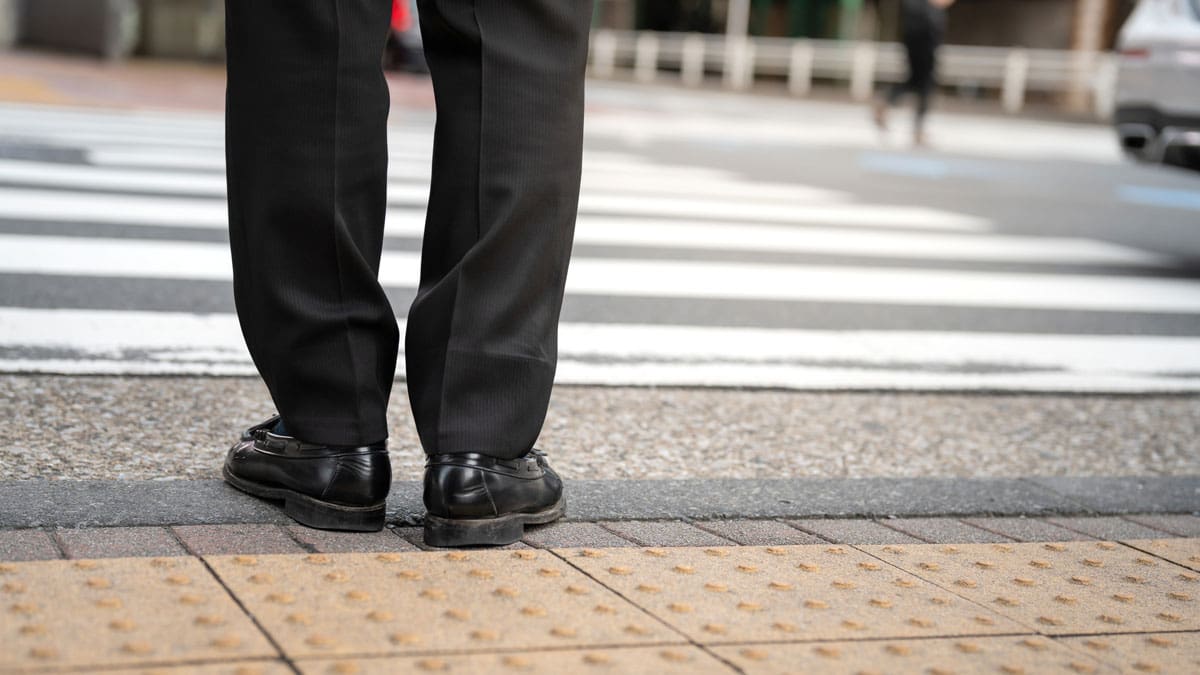 persons-feet-at-the-edge-of-a-curb-ramp-next-to-a-crosswalk