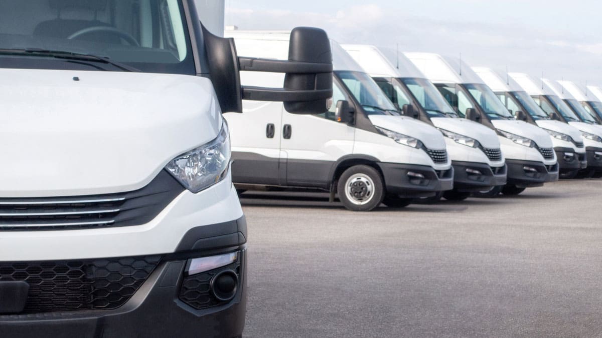 row-of-white-commercial-vans-parked-in-a-lot