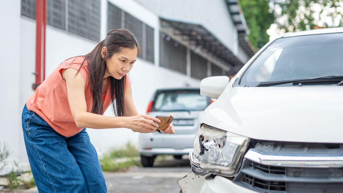 woman-inspecting-the-damaged-front-bumper-of-a-white-car