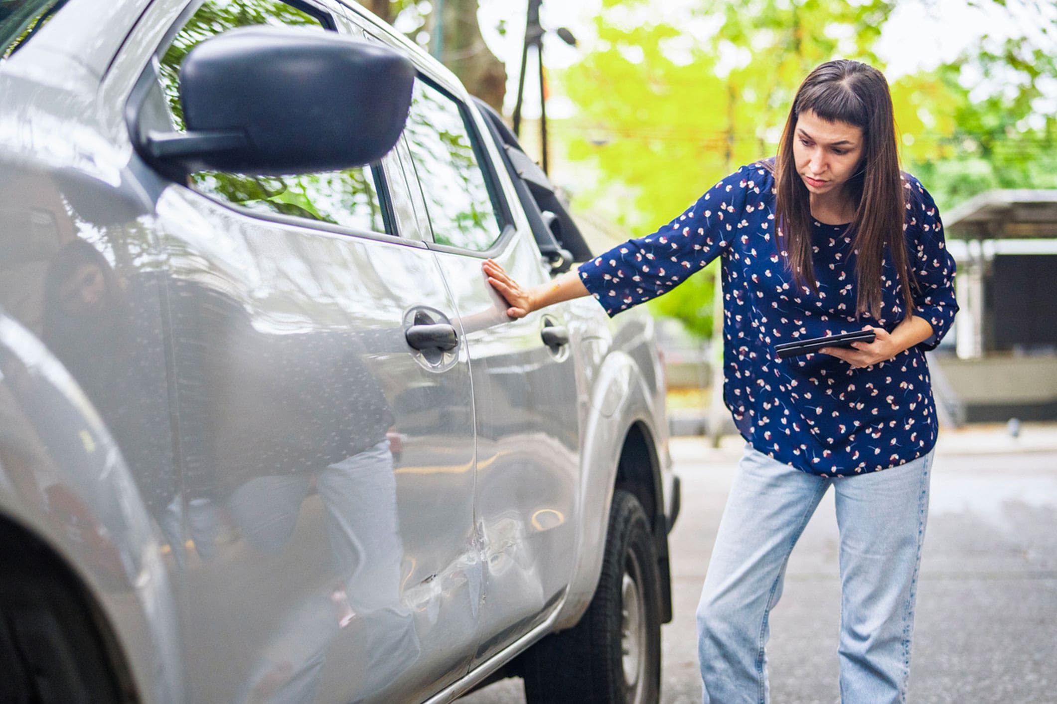 woman-standing-beside-her-damaged-car-at-the-roadside